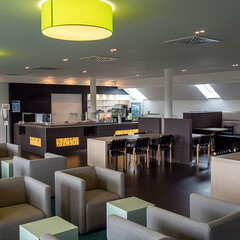 Cafeteria mit vielen Sitzmöglichkeiten und Theke mit Essensauswahl